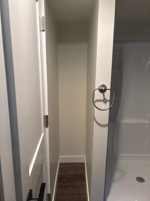White closet shelves viewed through an open bathroom doorway.